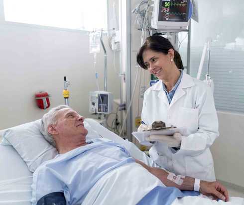 Ärztin lädt im Krankenhausbett liegenden Patienten auf