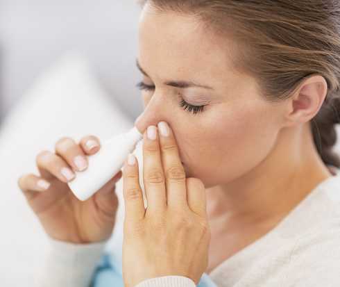 Eine junge Frau benutzt Nasenspray