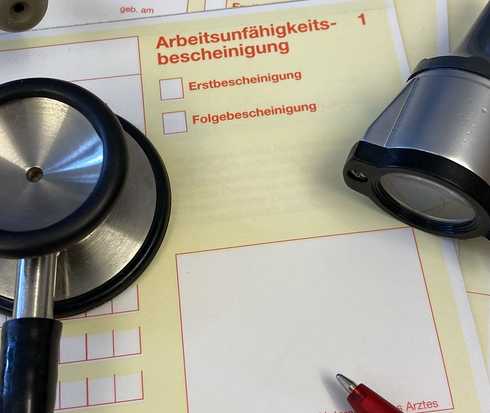 Auf dem Tisch eines Arztes liegt die Arbeitsunfähigkeitsbescheinigung für einen Patienten