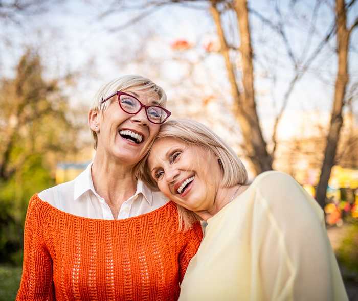 Zwei Frauen liegen sich in den Armen und lachen herzlich