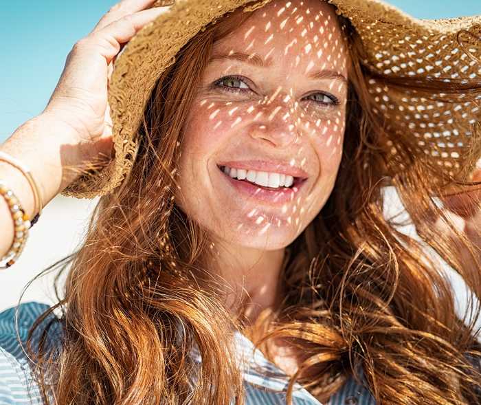 Junge Dame lächelt und trägt einen Sonnenhut