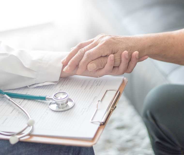 Eine Ärtzin hält die Hand einer Transplantierten